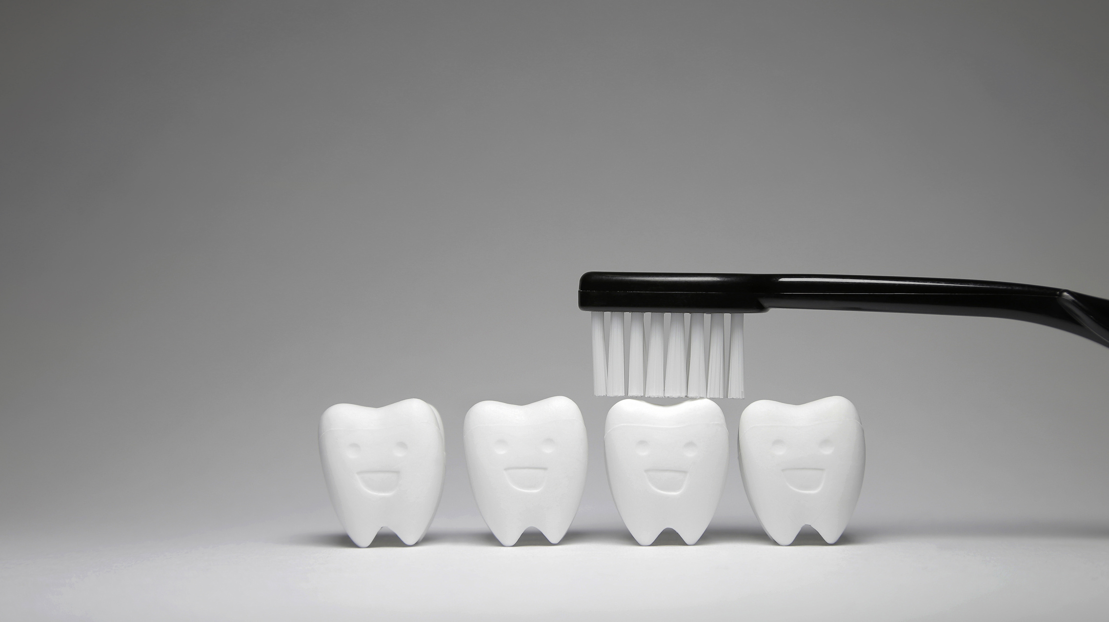 Black Toothbrush on Tooth model in happy emotion and blue, if brush the teeth, teeth will good healthy